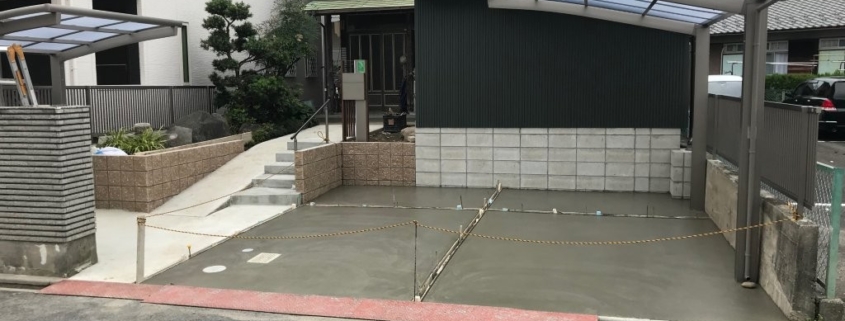 カーポートとフェンスを設置した完成後の駐車場。土間コンクリートが全面に打設され、段差解消スロープとアプローチが整った外構全景