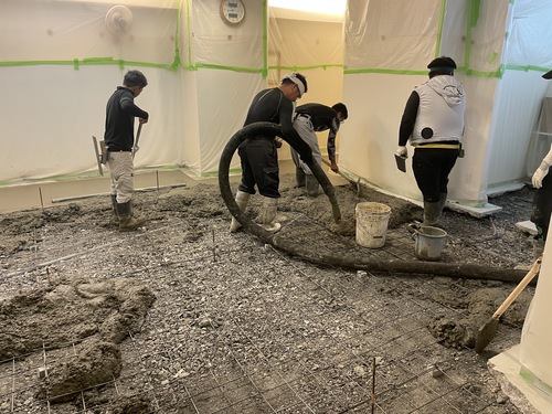 複数人で土間コンクリート打設を進めている店舗床補修工事の施工中写真